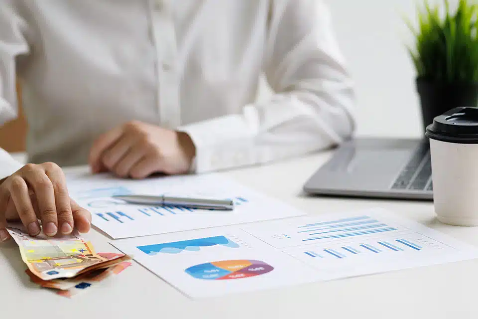 Person analyzes financial charts on desk.